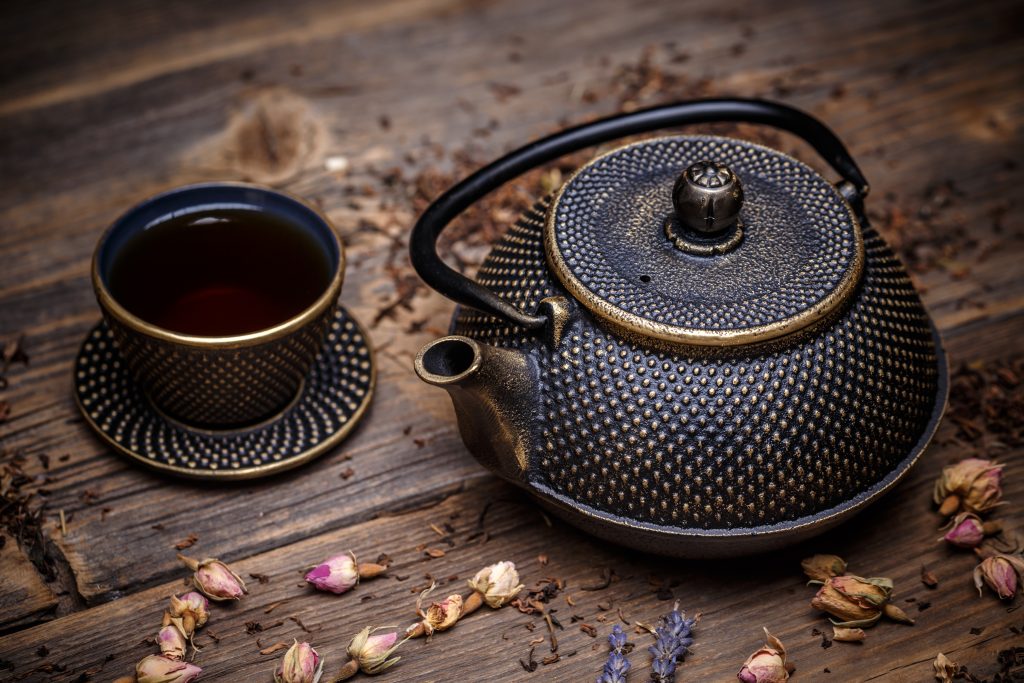 Asian tea set with iron teapot and small bowl on wooden background