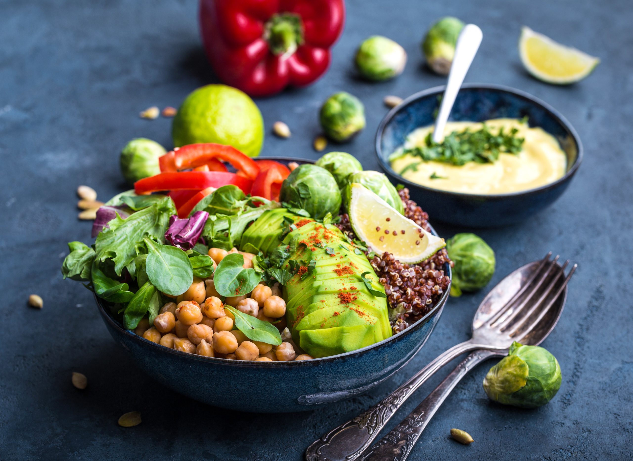 Bowl with healthy salad and dip. Close-up. Buddha bowl with chickpea, avocado, quinoa seeds, red bell pepper, fresh spinach, brussels sprout, lime mix. Vegetarian salad. 30-day plant-based Diet plan