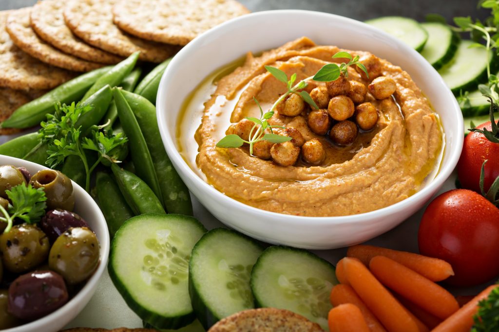 Hummus and fresh vegetables snack platter with grain salad and crackers