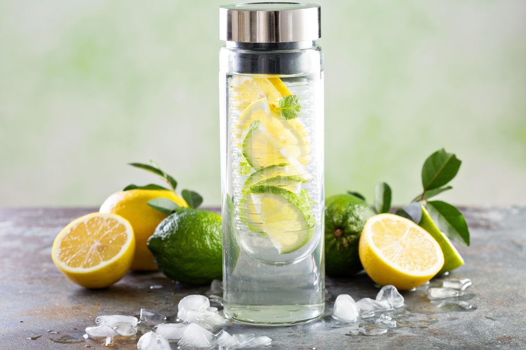 Cold and refreshing infused detox water with lime and lemon in glass bottle