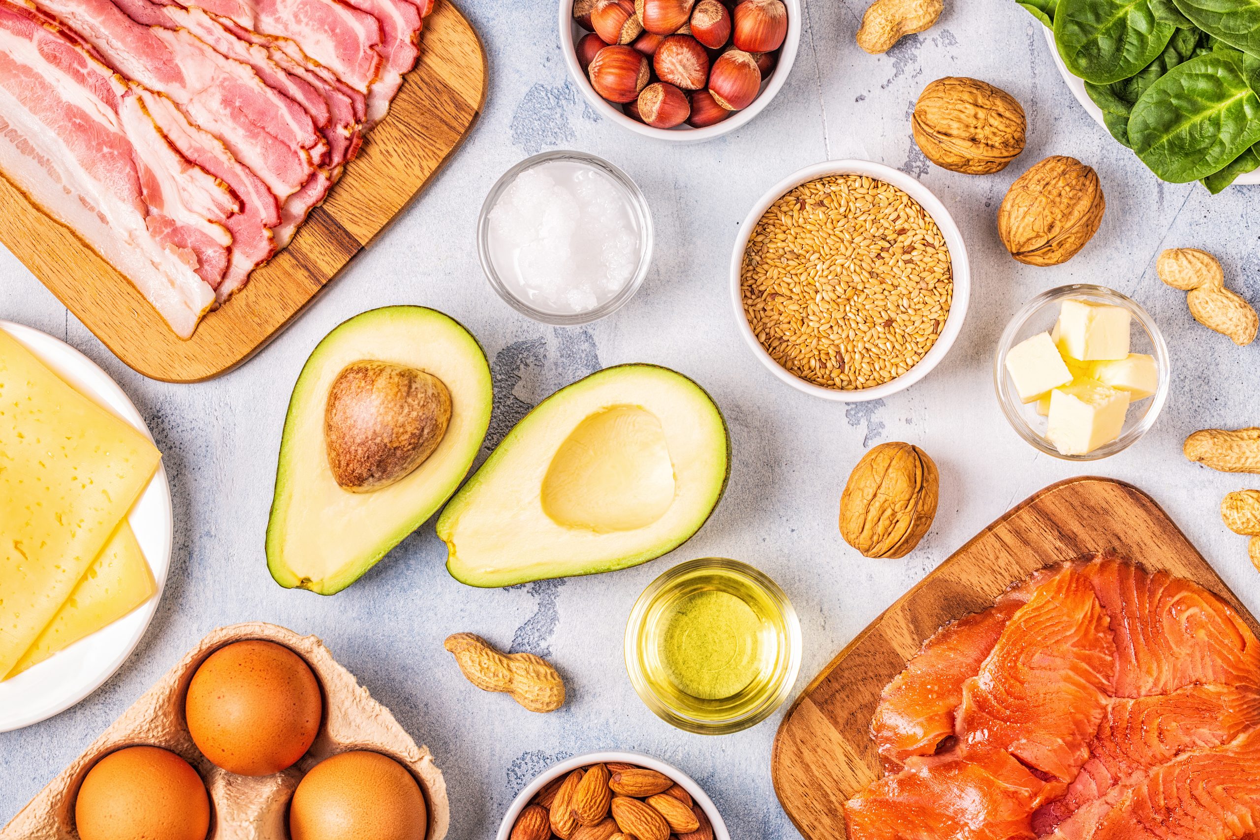 Healthy ingredients for South Beach Diet Phase 2, including bacon, avocado, nuts, eggs, cheese, and salmon, arranged on a light background.