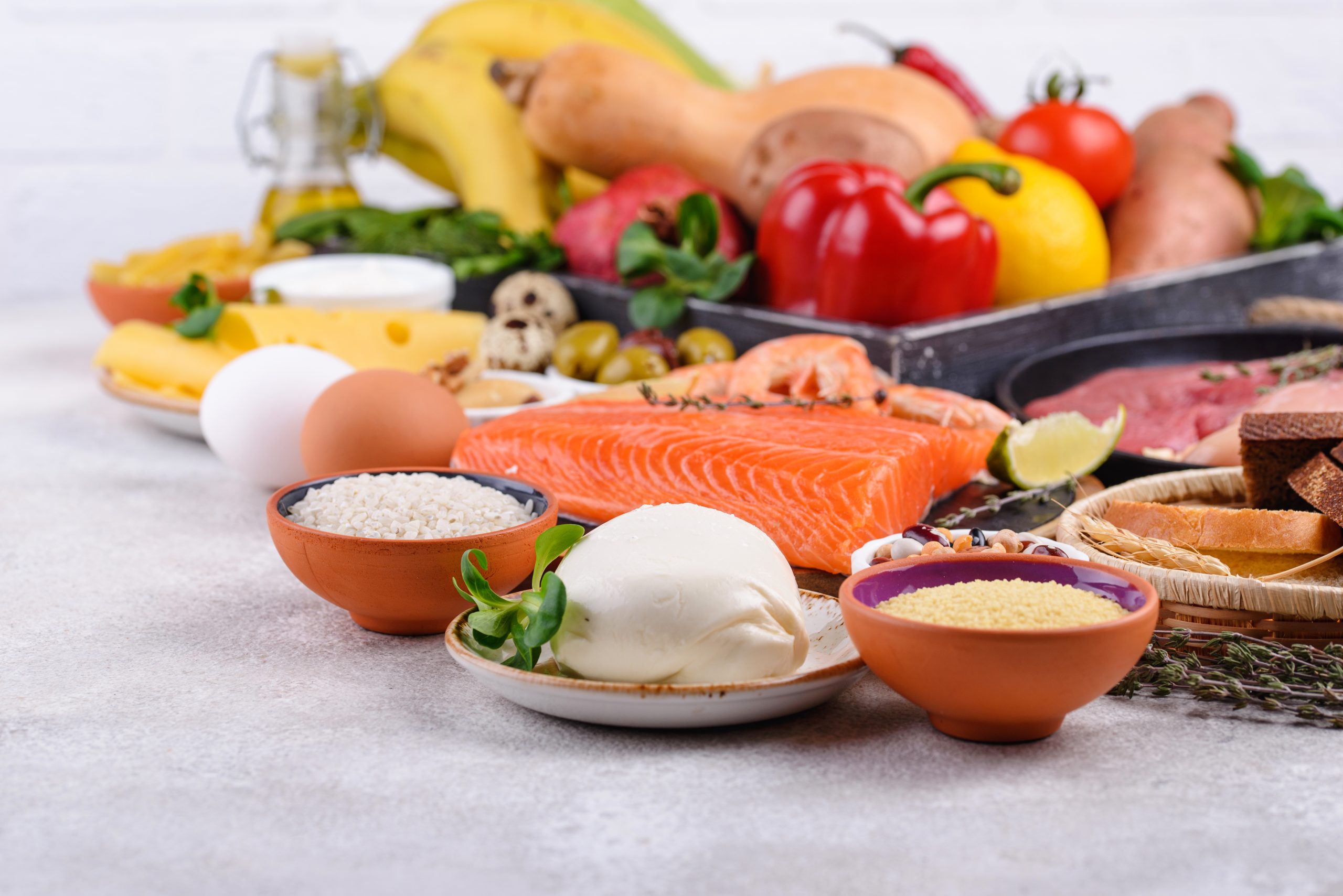 Assorted foods including salmon, mozzarella cheese, fruits, vegetables, and grains, representing a balanced Mediterranean diet, highlighting the nutritional benefits of the Mediterranean diet vs Keto diet.